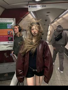 Woman with windblown hair in a subway station wearing a leather jacket and shorts