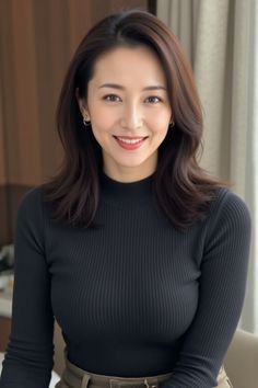 Woman with long hair wearing a black turtleneck top and smiling indoors