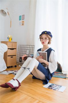 Woman in a blue beret and cat thigh highs sitting on a wooden floor