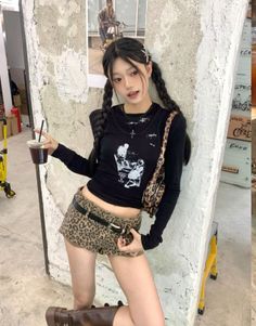 Woman with braided black hair wearing a crop top and leopard print shorts indoors