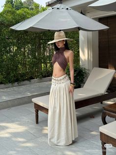 Woman in a straw hat, halter top, and long skirt outdoors