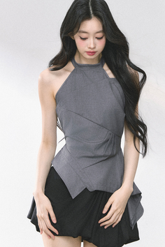Woman with long black hair wearing a gray top and black skirt in a studio