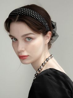 Woman with a polka dot headband and beaded necklace looking at the camera