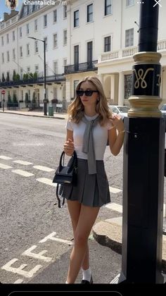 Woman in a white t-shirt and pleated skirt on a city street