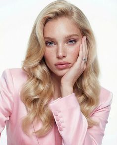 Woman with blonde hair and freckles wearing a pink blazer and a ring