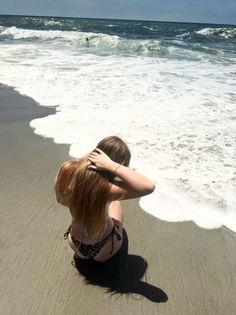 Woman in a leopard print bikini sitting on the beach with her back to the ocean