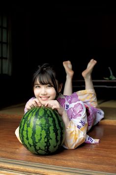Woman in a yukata lying down with a watermelon, smiling at the camera