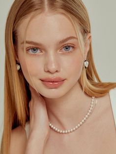 Young woman with blonde hair and blue eyes wearing pearl jewelry