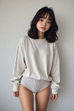 Woman with short black hair wearing an oversized sweatshirt and underwear indoors