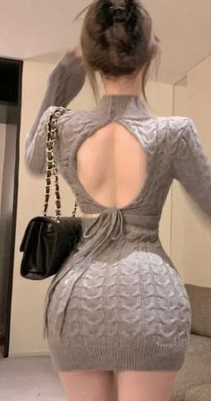 Woman in a gray knitted dress with an open back and a black handbag
