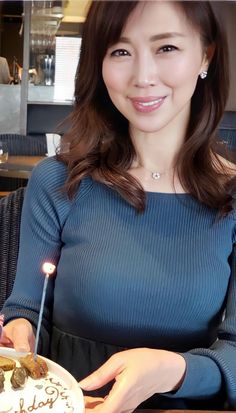 Woman with long brown hair holding a birthday cake with a lit sparkler
