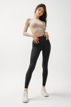 Woman in black leggings and a long sleeve top posing in a studio