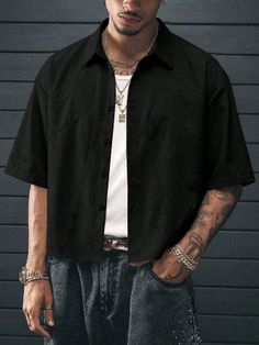 Man in a black shirt and jeans with gold chains and tattoos