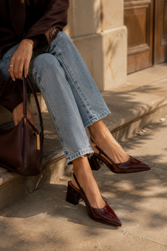 Person in light wash jeans and brown blazer with slingback heels and handbag