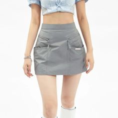Woman in a grey mini skirt and blue crop top with exposed midriff