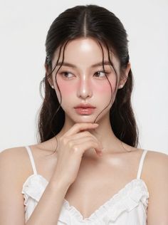 Woman with wet hair and pink blush wearing a white top and pearl earrings