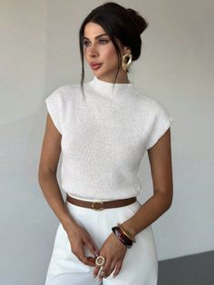 Woman in a white top and brown belt with gold earrings and an updo