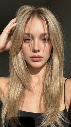 Woman with long blonde hair and a heart necklace in soft lighting