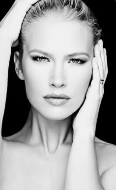 Black and white portrait of a woman with slicked back hair and bare shoulders