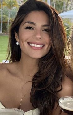 Woman with long brown hair and dimples smiling outdoors