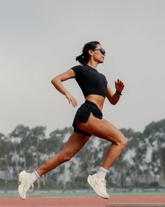 Woman in athletic wear running on a track with trees in the background
