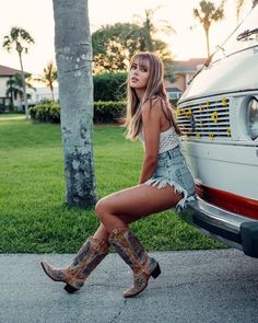 Woman in denim shorts and cowboy boots sitting on a van bumper at golden hour
