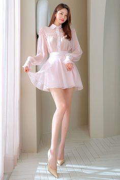 Woman in a sheer pink dress and high heels posing indoors