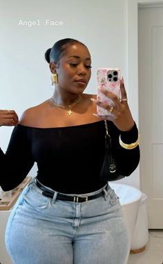 Woman in an off-shoulder top and light wash jeans taking a mirror selfie