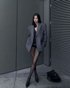 Woman in an oversized blazer and patterned tights posing outdoors