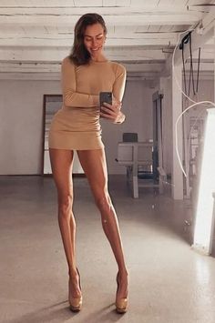 Woman in a tight mini dress and high heels taking a mirror selfie