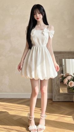 Woman in a white dress with bows and ruffled sandals indoors