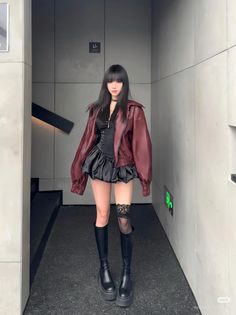 Woman with long black hair in a red leather jacket and black dress indoors