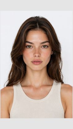 Woman with long brown hair and freckles wearing a tank top against a white background