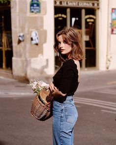 Woman with short hair holding a wicker basket with flowers on a street