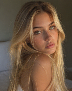 Blonde woman with green eyes and freckles looking over her shoulder