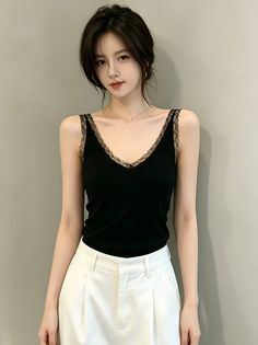 Woman with black hair wearing a black lace-trim camisole and white pants