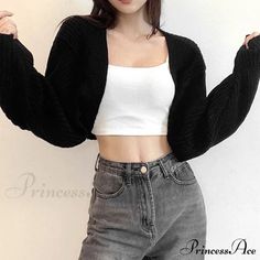 Woman in a black cardigan, white crop top, and grey jeans