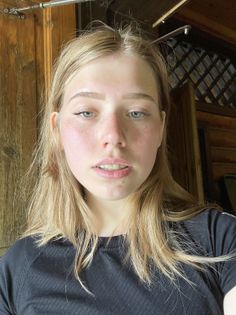 Young woman with blonde hair and braces wearing a black shirt indoors