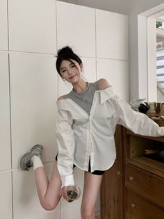 Woman in a white shirt and grey tank top posing indoors
