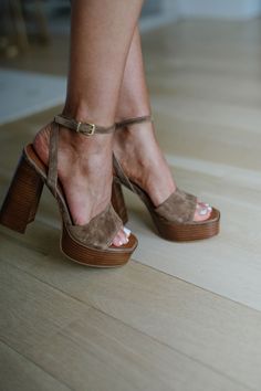 Close up of feet wearing brown suede platform heels with white pedicure