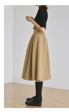 Woman in a black top and a beige midi skirt with black socks and loafers
