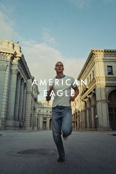 Man in a white t-shirt and blue jeans running on a city street