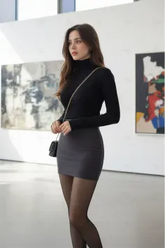 Woman in a black turtleneck and grey mini skirt with a shoulder bag indoors