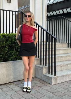 Woman with blonde hair in a red top and black mini skirt outdoors