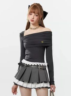 Woman in a black off-shoulder top and pleated skirt with a black bow in her hair