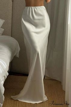 Person in a white satin skirt standing in a bedroom