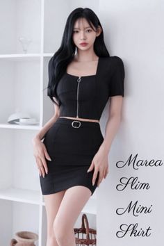 Woman with long black hair wearing a black crop top and mini skirt indoors