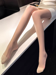 Woman wearing nude pantyhose and a short skirt, sitting indoors