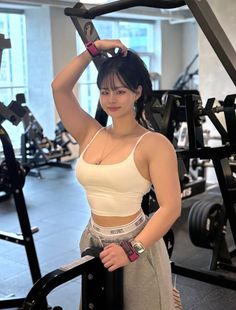 Woman in a white crop top and sweatpants posing in a gym