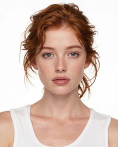 Woman with red hair and blue eyes wearing a white tank top